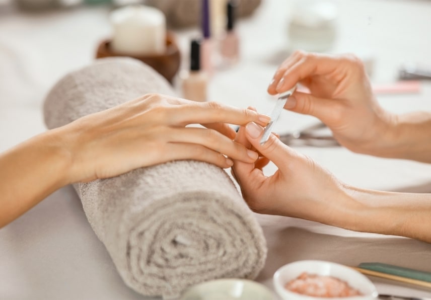 stock photo close up shot of a woman in a nail salon receiving manicure by beautician with metal nail file 2012714210 transformed 1